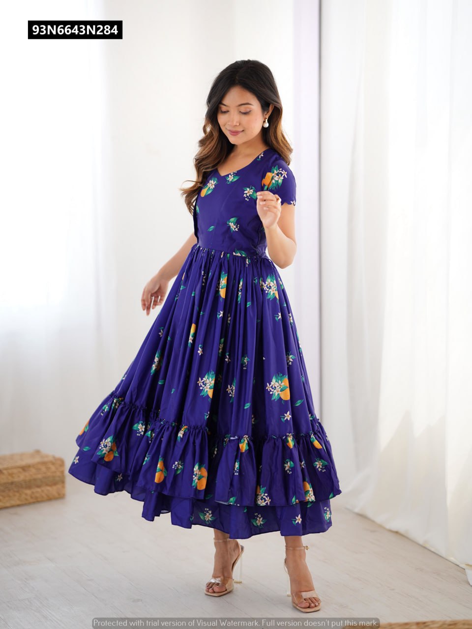 TRENDBUY Royal Blue Muslin Silk gown with all-over floral print, featuring a model gracefully twirling, showcasing the double frill hem.