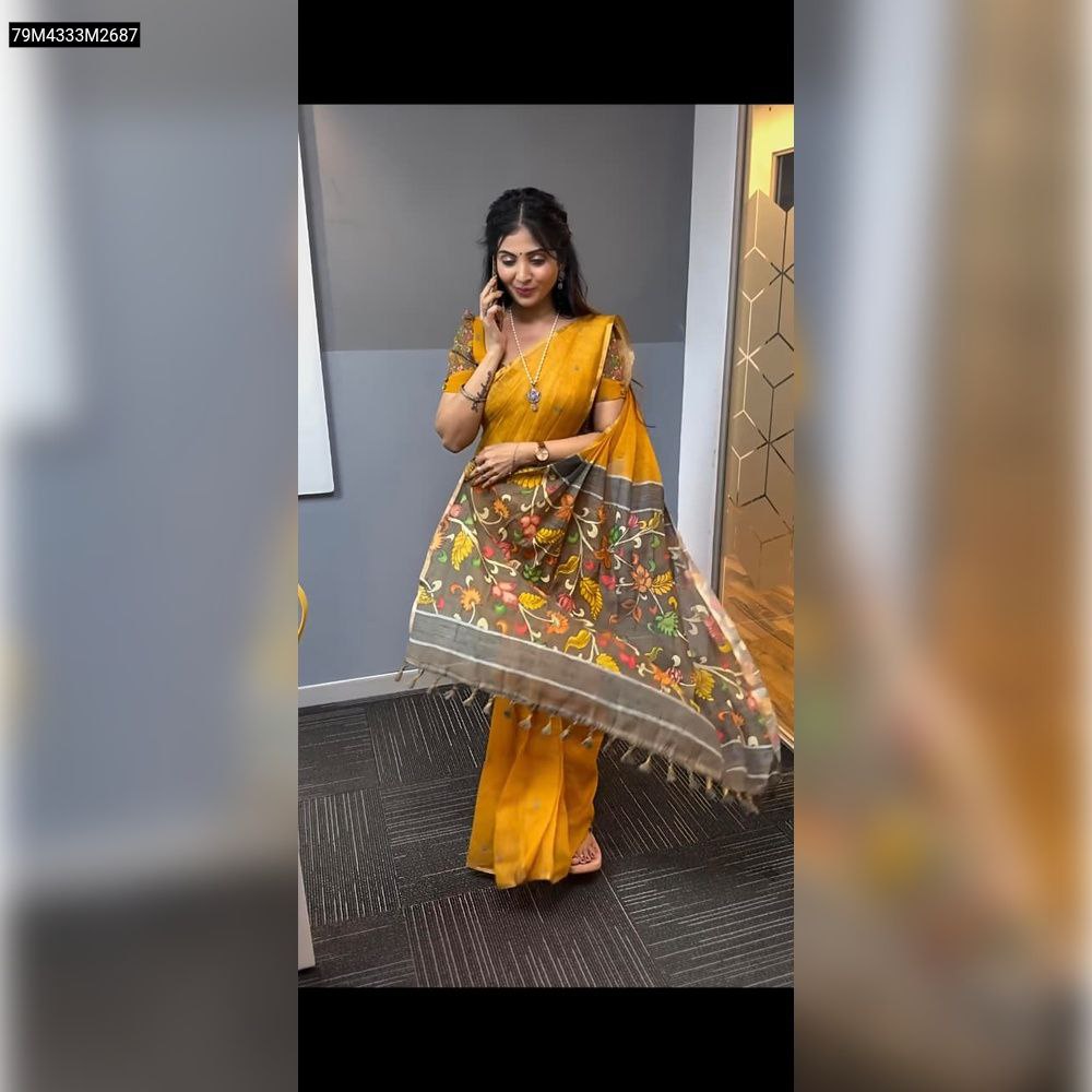 Model wearing TRENDBUY Mustard Yellow linen saree with flowing brown Kalamkari print pallu and tassels in a modern office setting, showcasing the drape and design.