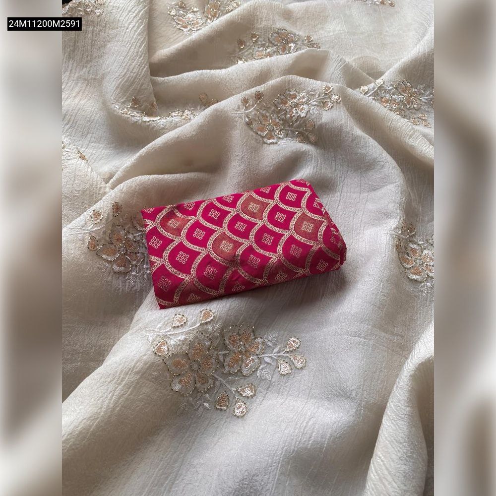 Overhead view of an off-white bember crush saree with gold floral handwork embroidery and a folded pink brocade blouse piece.