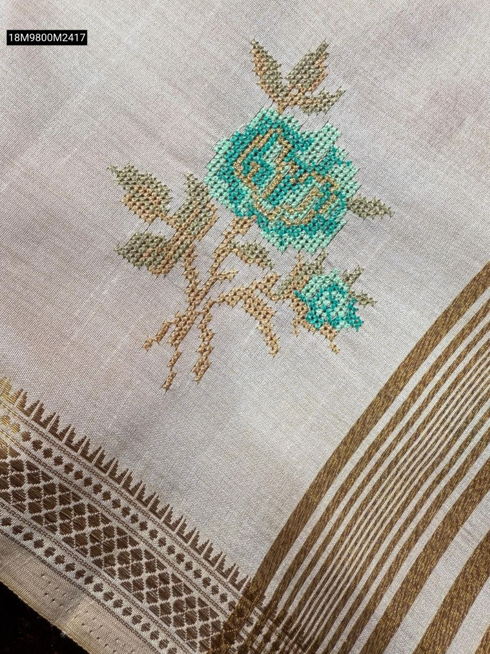 Close-up of intricate multi-colored Kashmiri thread embroidery on off-white fabric
