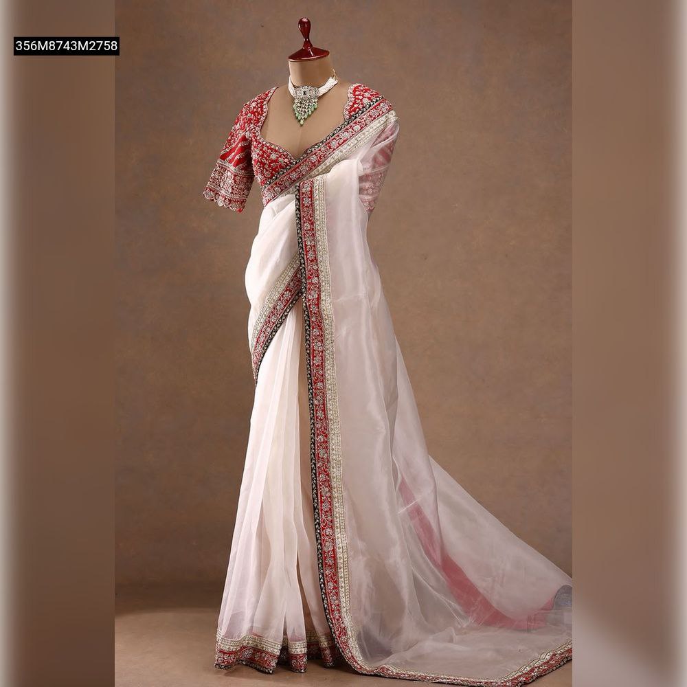 Full-length mannequin display of the TRENDBUY off-white space silk saree elegantly draped, featuring a vibrant red embroidered blouse with delicate sleeves, showcasing the complete traditional Indian attire and its graceful flow against a brown background.