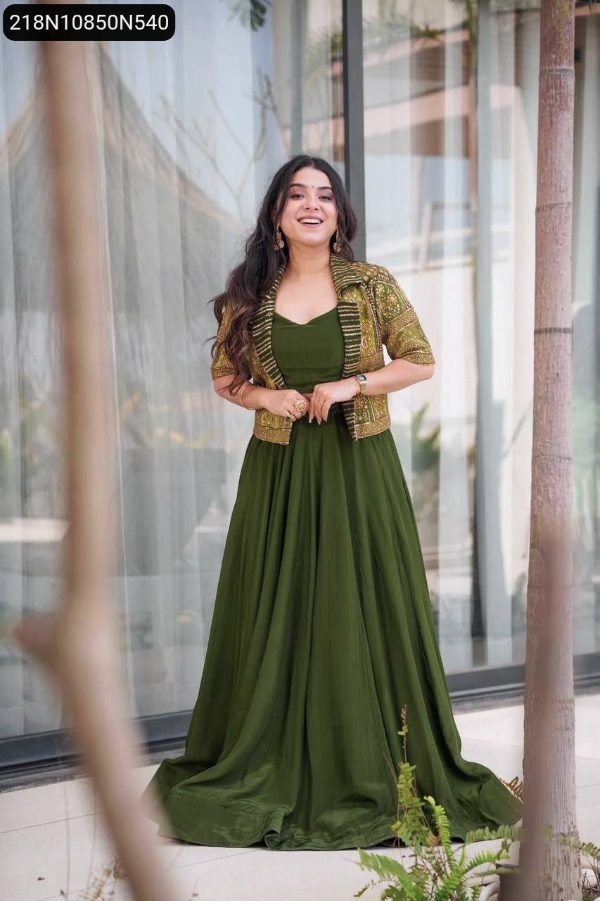 Full-body model shot of the olive green Koti Lehenga Choli set, model smiling confidently, standing against a blurred outdoor background.