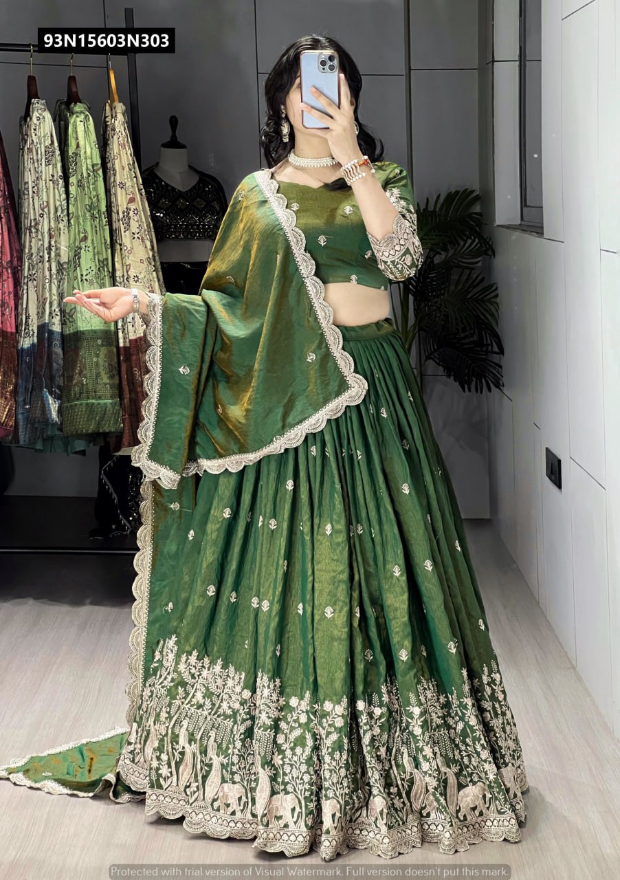 Full shot of model in a shimmering olive green embroidered lehenga choli set, showcasing the complete outfit with dupatta draped over her arm.