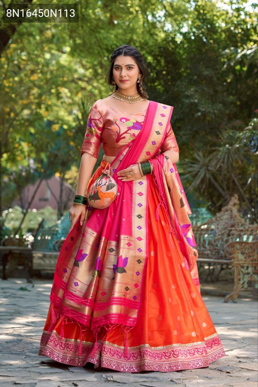TRENDBUY Paithani Jacquard Silk Lehenga Choli in vibrant orange with intricate Zari weaving, worn by a model in an outdoor garden setting, holding a matching potli bag.