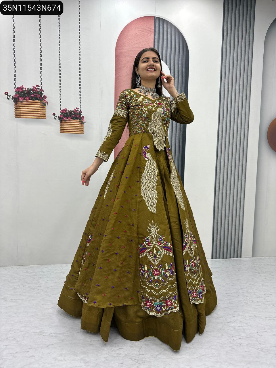 Full body shot of a smiling woman in an olive green embroidered lehenga set, posing elegantly, highlighting the vibrant work.