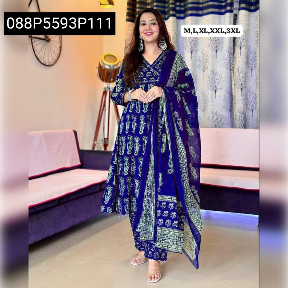 Full body shot of a model wearing a royal blue TRENDBUY kurti set with light green floral Saganeri print, mirror work neckline, matching pants, and dupatta, standing in a living room.