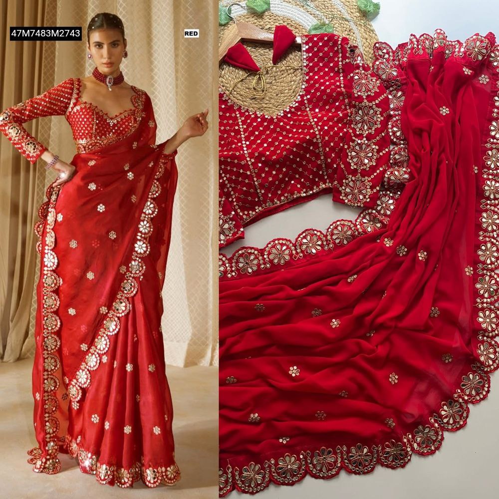 Full shot of a model elegantly draped in a vibrant red TRENDBUY Faux Georgette saree, showcasing intricate gold sequence work and original mirror embellishments along the scalloped border, paired with a matching embroidered long-sleeve blouse.
