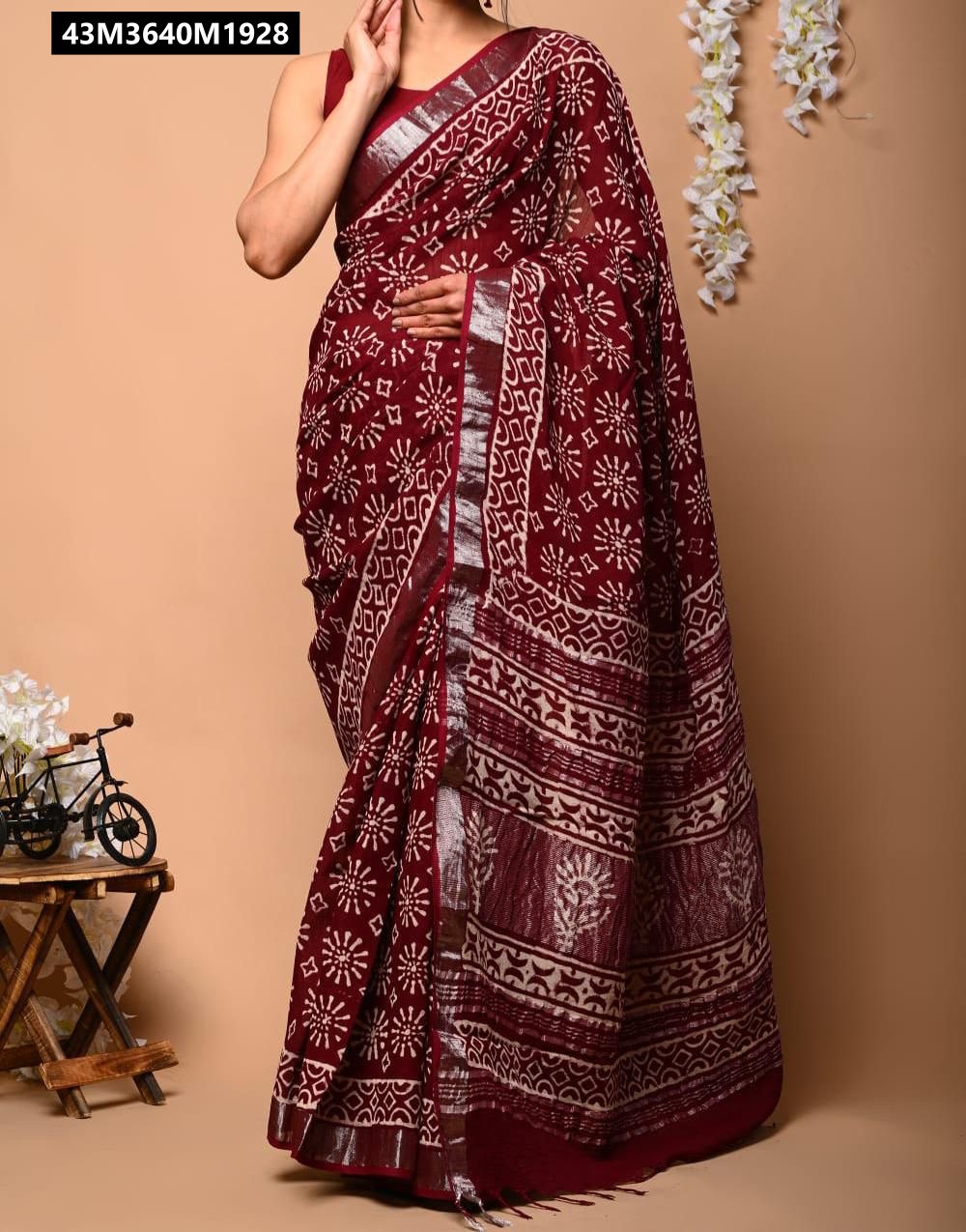 Model wearing maroon linen saree with white floral batik print and silver zari border