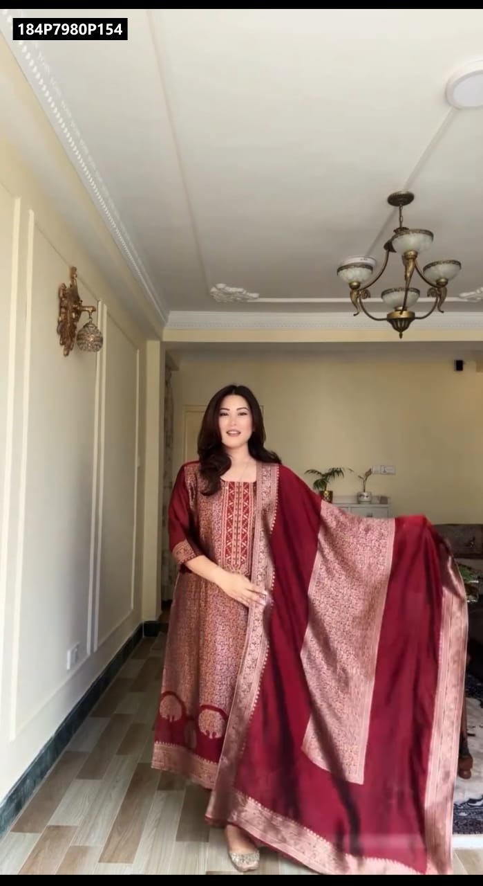 Model posing gracefully in a full-length maroon Banarasi suit set with golden zari weaving and matching dupatta.