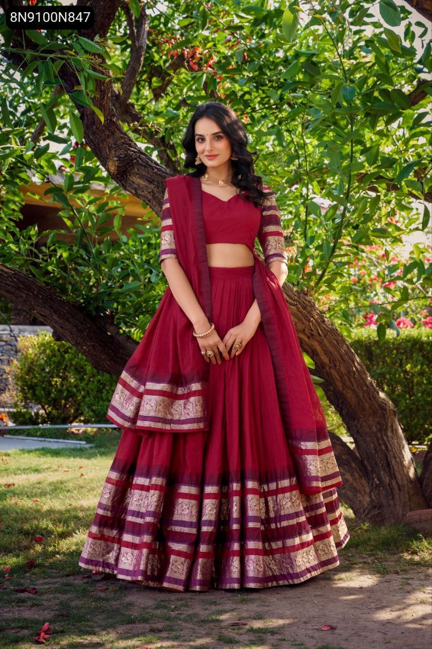 Front full body shot of a model in a majestic maroon Chanderi lehenga choli with ornate zari weaving borders, smiling charmingly.
