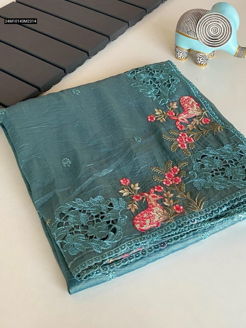 Folded Teal Green pure crush silk saree, showcasing intricate floral and peacock embroidery with cut-work lace border.