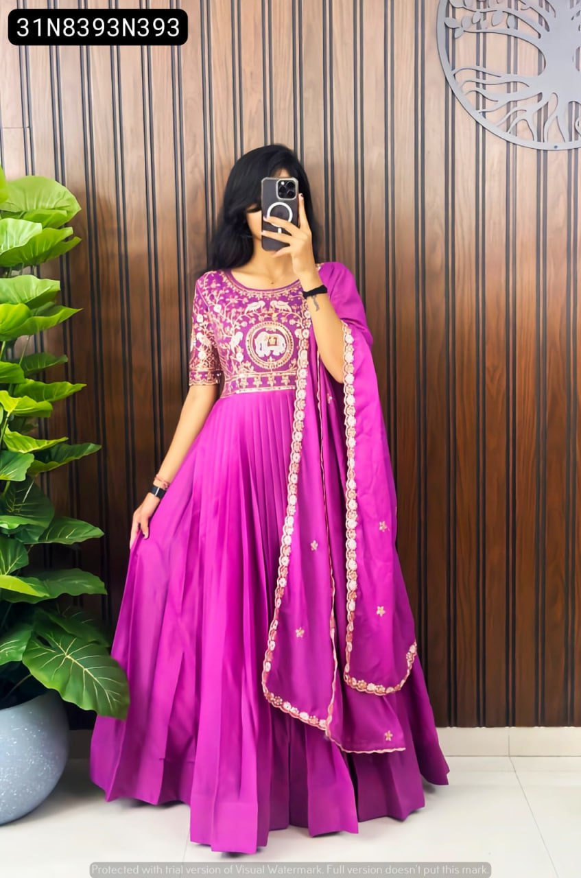 Full shot of a model wearing a vibrant magenta TRENDBUY georgette silk embroidered gown with matching dupatta, standing against a wooden panel wall.