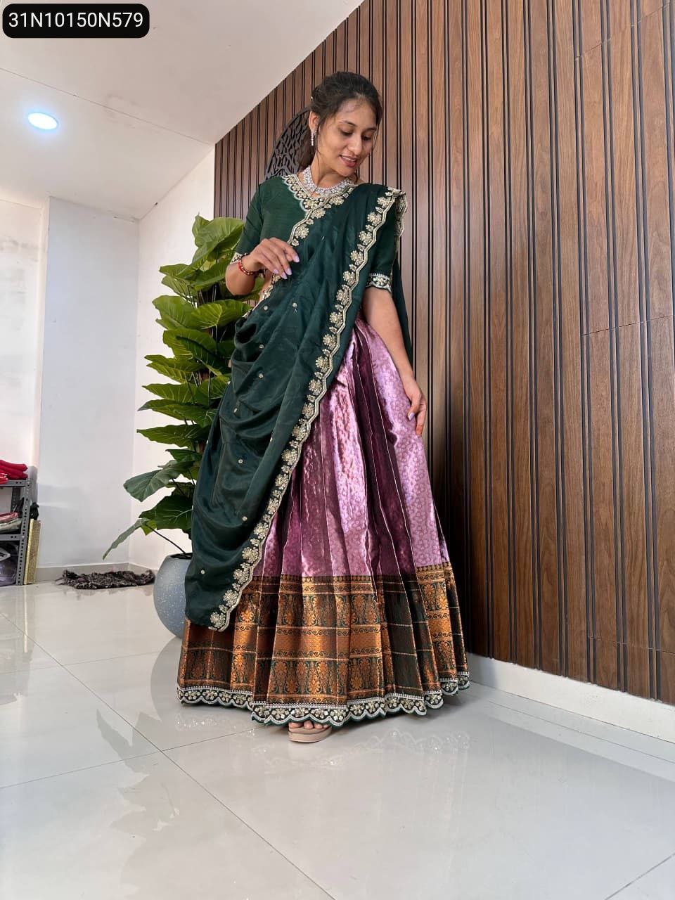 TRENDBUY model in dark green and pink pure silk half saree lehenga, gracefully looking down.