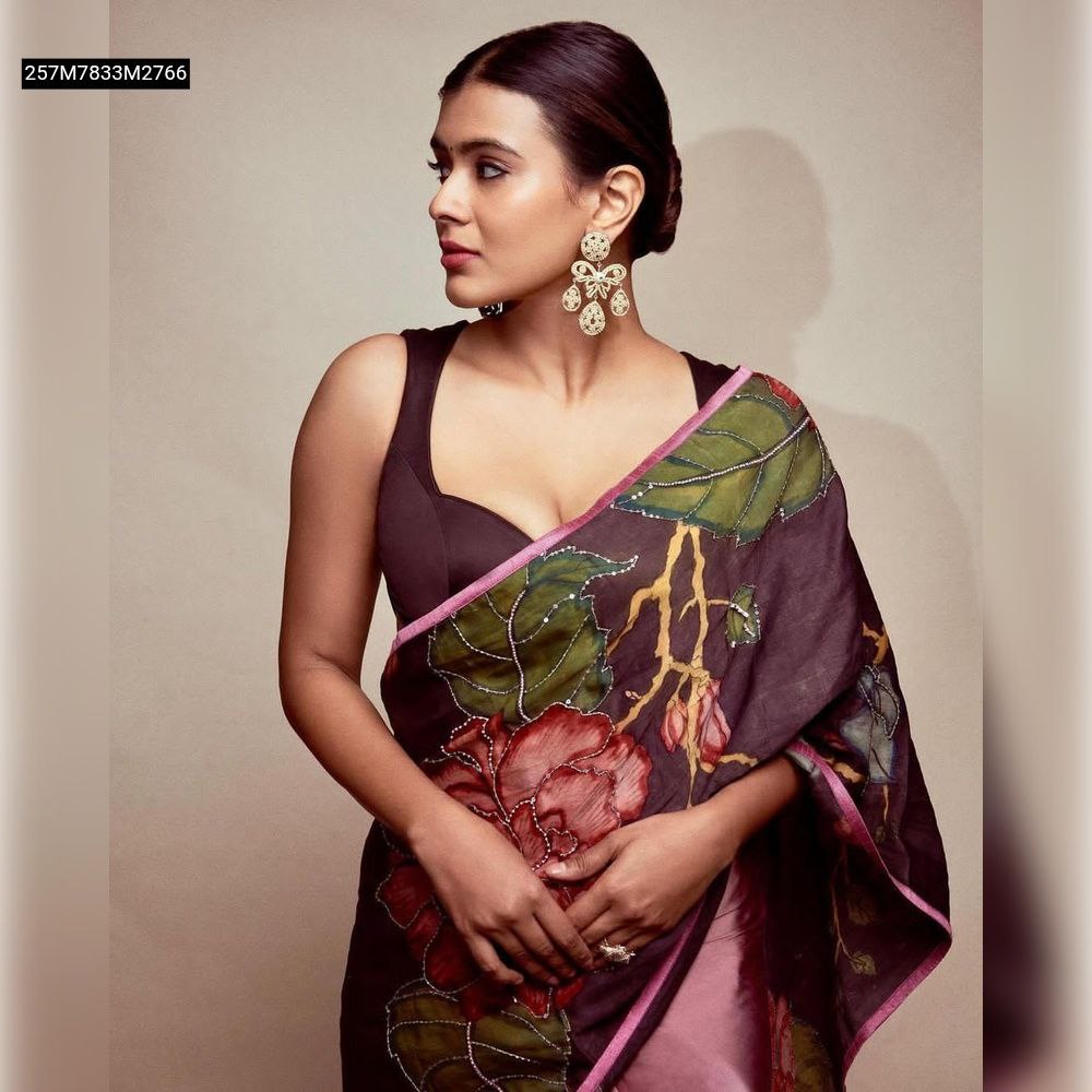 TRENDBUY model in dark maroon Kalamkari silk saree with handwork, showcasing floral design and pink border, paired with statement earrings, side profile.
