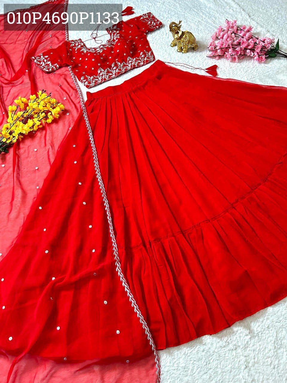 Overhead view of TRENDBUY Red Georgette Lehenga Choli set with intricate silver embroidery on the blouse and a matching frill-work lehenga, displayed with a delicate butta-work dupatta and festive decorations.