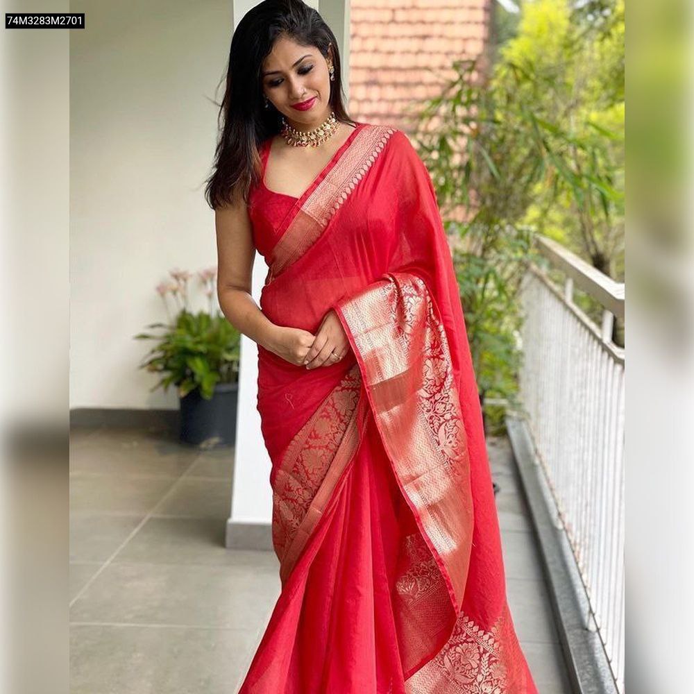 Graceful full-length shot of a woman on a balcony, beautifully draped in the TRENDBUY Red Lichi Art Silk Saree, showcasing its vibrant color and intricate jacquard border.