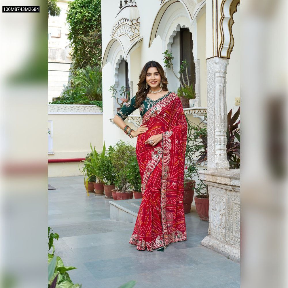 TRENDBUY model showcasing a beautiful red pure Bandhrej saree with a green embroidered blouse, standing elegantly outdoors.