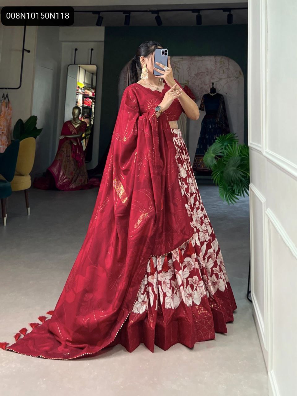 Model showcasing TRENDBUY Red Tussar Silk Lehenga Choli with white floral and gold foil print, full view of the flowing skirt and richly printed dupatta in a boutique setting.