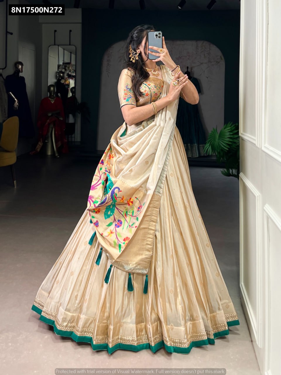 Model posing dynamically in a TRENDBUY Cream Gold Shimmer Paithani Lehenga Choli, highlighted by a striking green border and peacock-inspired Paithani zari work on the flowing dupatta.