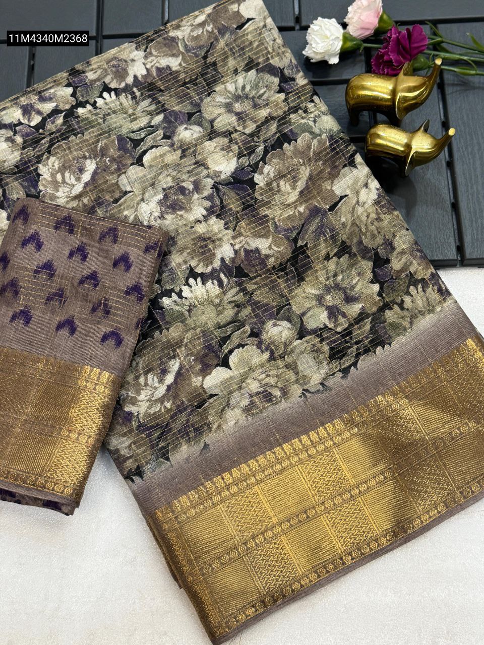 TRENDBUY Brown-Mauve soft cotton saree with intricate floral print, prominent gold zari border, and a complementary ikkat pattern blouse piece, displayed elegantly.