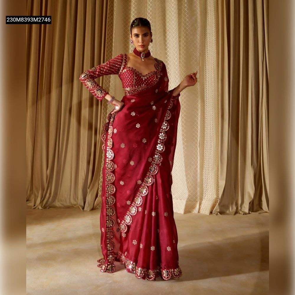 Full shot of a model wearing a TRENDBUY Maroon Georgette Silk Saree with intricate silver mirror and sequin embroidery along the border and pallu, standing in front of golden curtains.