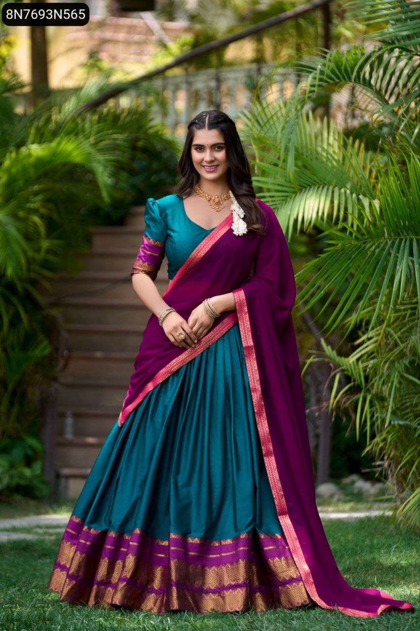 Model posing gracefully in a TRENDBUY South Style half saree lehenga set featuring a teal blue poly cotton lehenga with gold zari border, matching blouse, and a rich purple georgette dupatta, set against a lush garden backdrop.