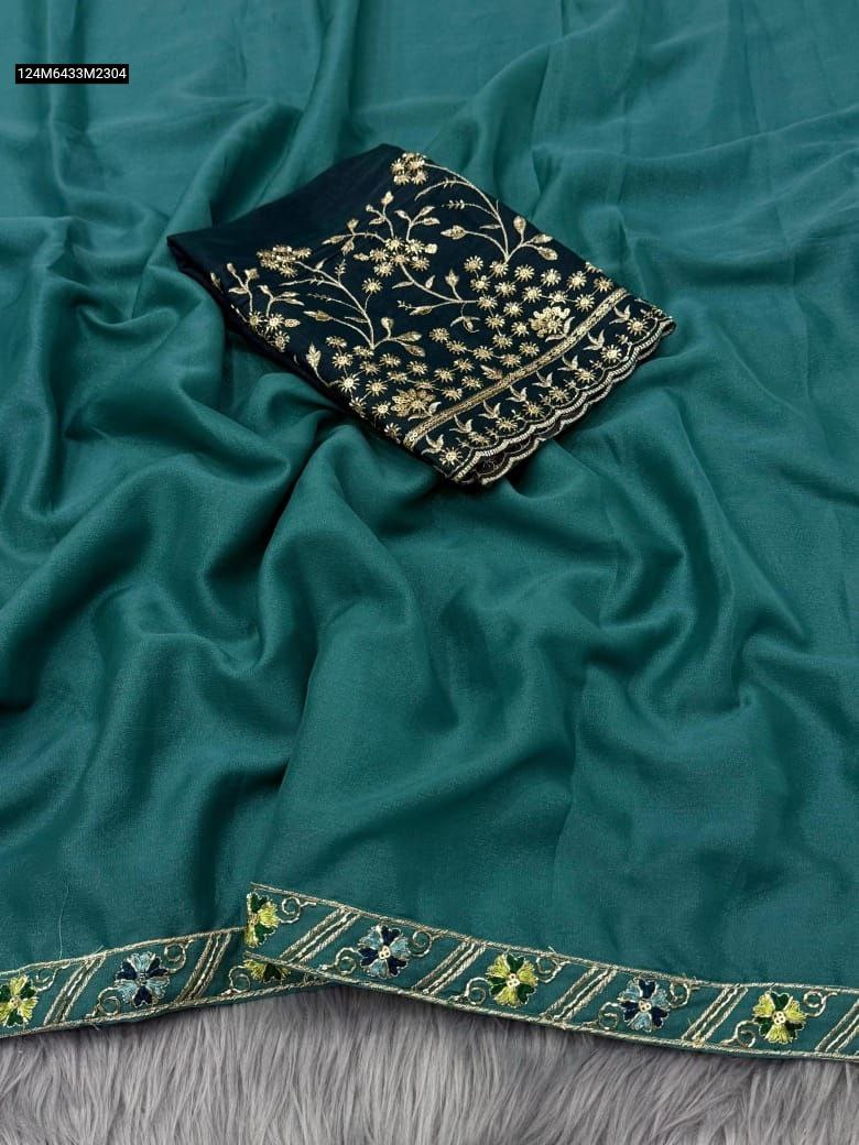 TRENDBUY Teal Star Georgette saree fabric with intricate floral handwork border and a dark green heavy handwork blouse piece, styled on a plush grey surface.