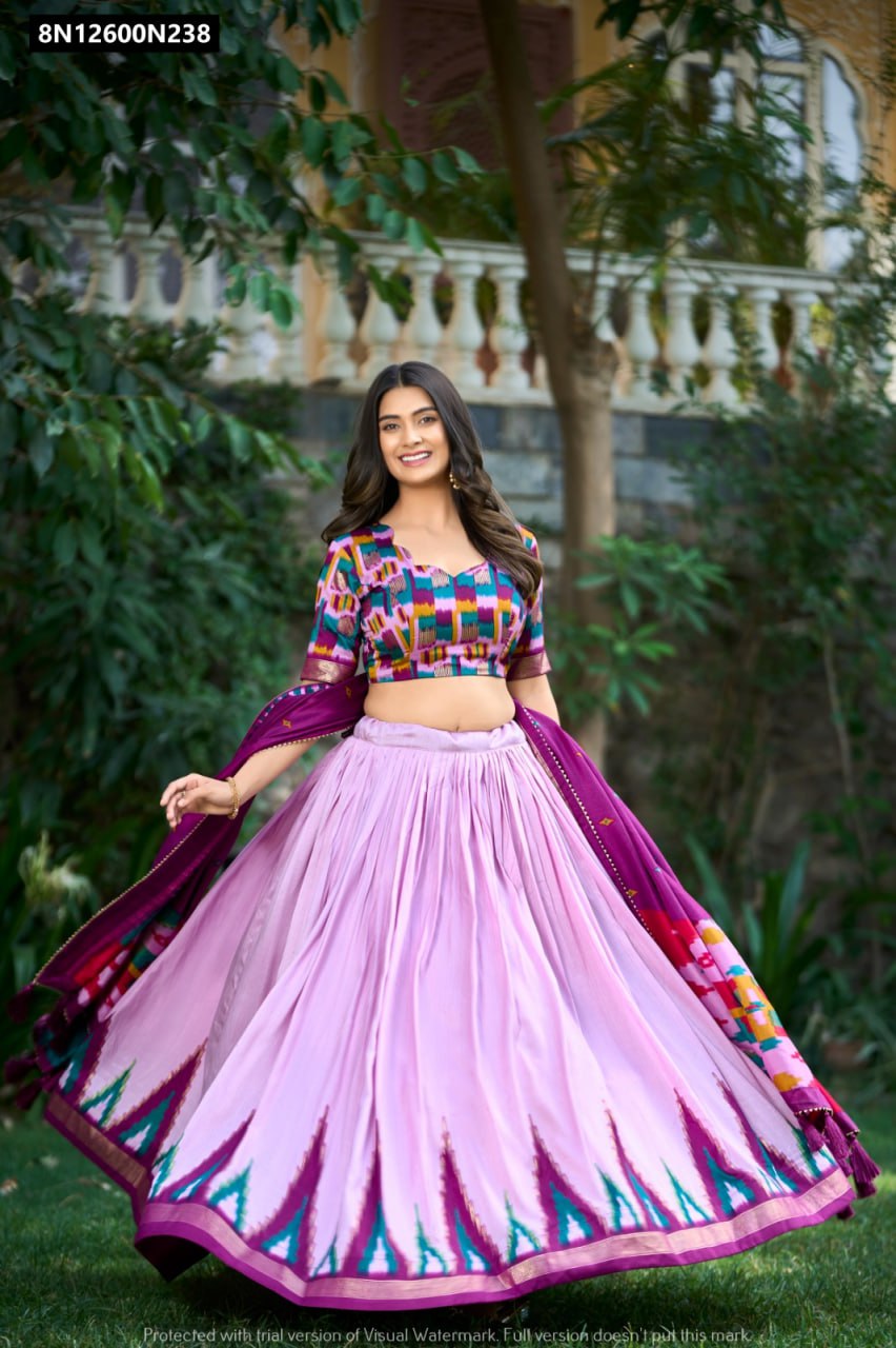 Smiling model showcasing a vibrant TRENDBUY Lavender and Multi-color Ikat Tasar Silk Lehenga Choli set with multi-color print blouse and dupatta, twirling in a lush garden.