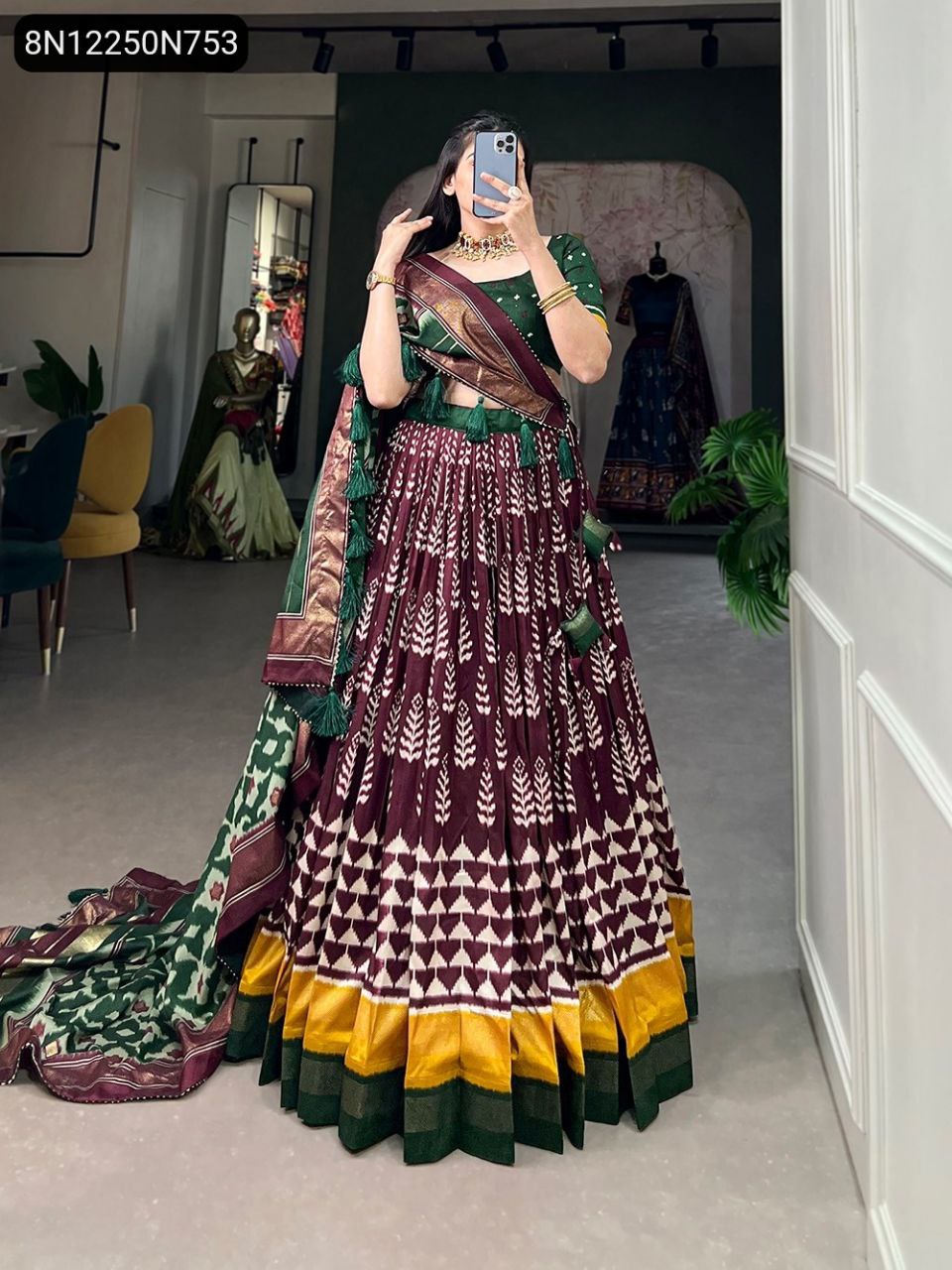 Full shot of model in a maroon lehenga with white geometric patterns, dark green blouse, and matching green and maroon printed dupatta.