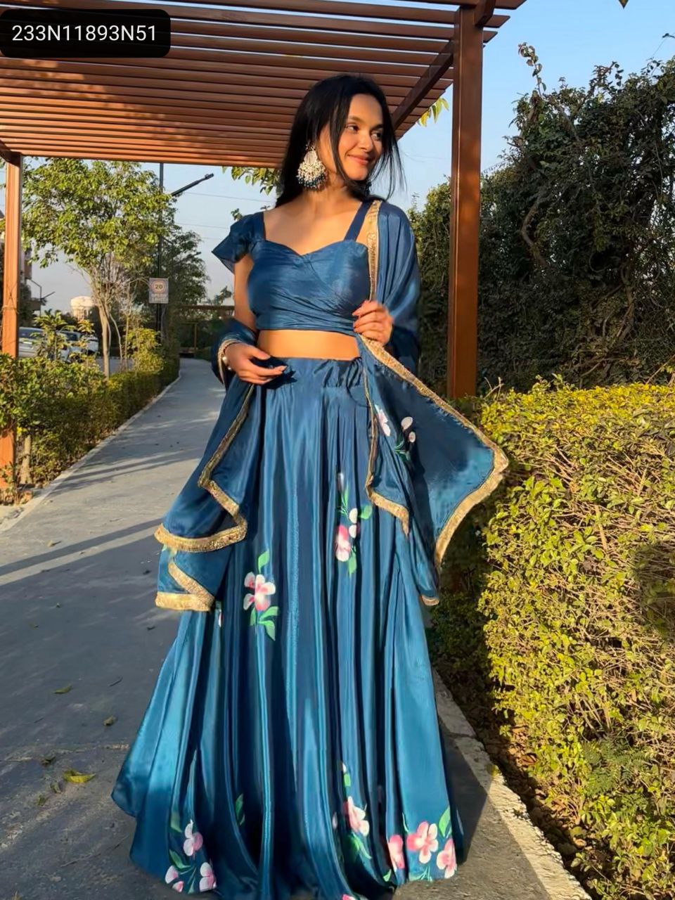 Main product image: Model elegantly walking in the TRENDBUY teal blue Chinon handpaint floral lehenga choli set in a garden path.