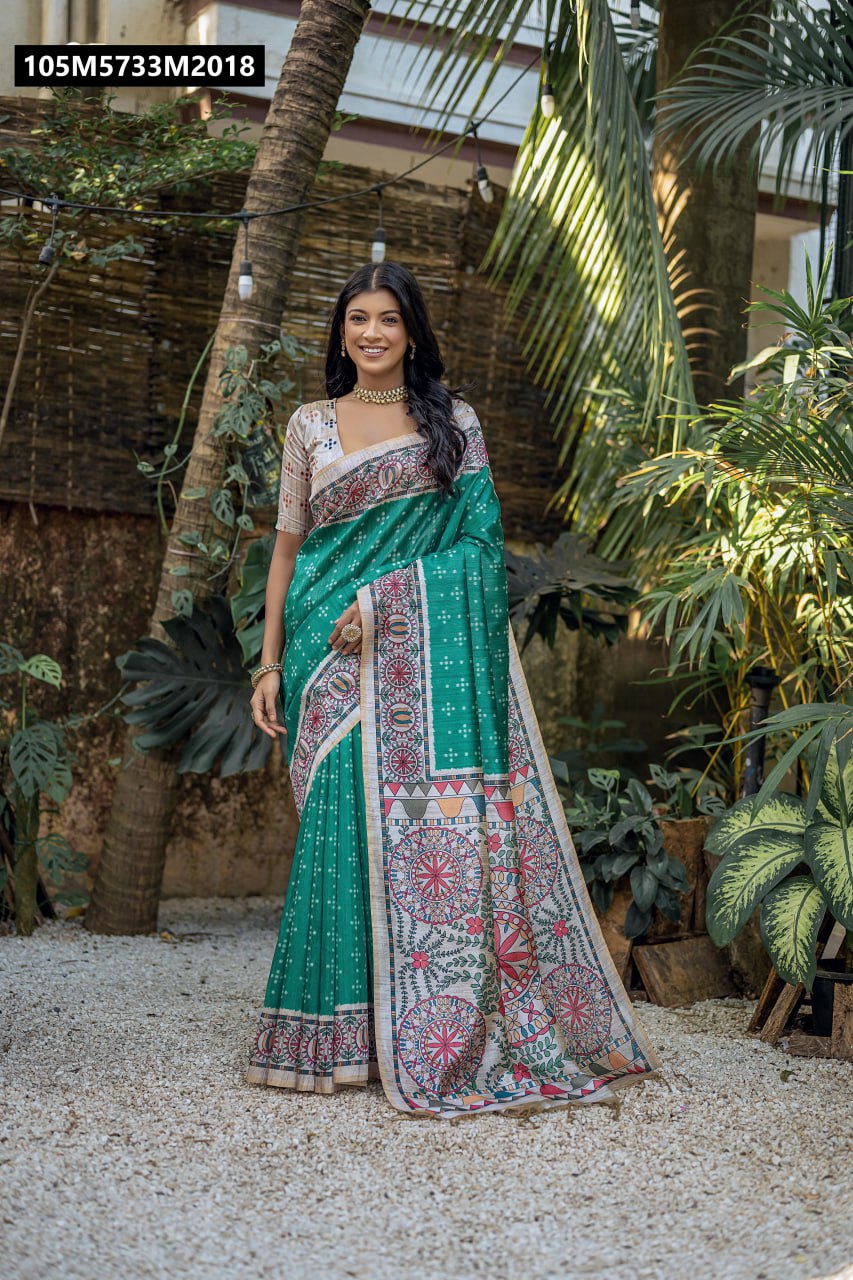 Full view of a model in a teal green Tussar silk saree with Madhubani pallu and Bandhani body, standing elegantly in a lush garden setting.