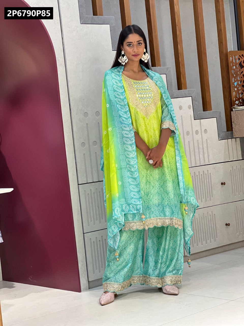 Full body shot of model wearing TRENDBUY vibrant green and blue Indian kurti palazzo set with sheer dupatta, hands clasped, showing intricate patterns.