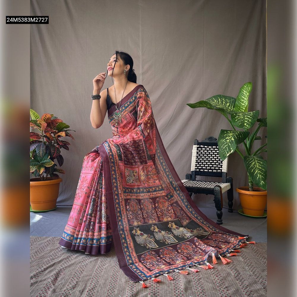 Model seated, showcasing a pink and maroon Kalamkari printed Poly Cotton saree with contrast pallu and tassels.