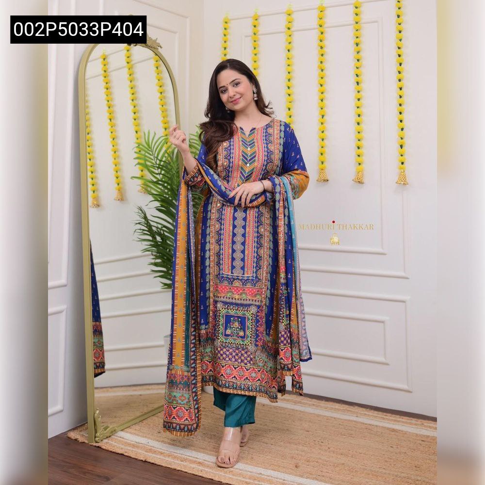 Full body shot of a model wearing the vibrant TRENDBUY multi-print Masleen kurti set with teal silk pants and dupatta, posing confidently in a decorated room.
