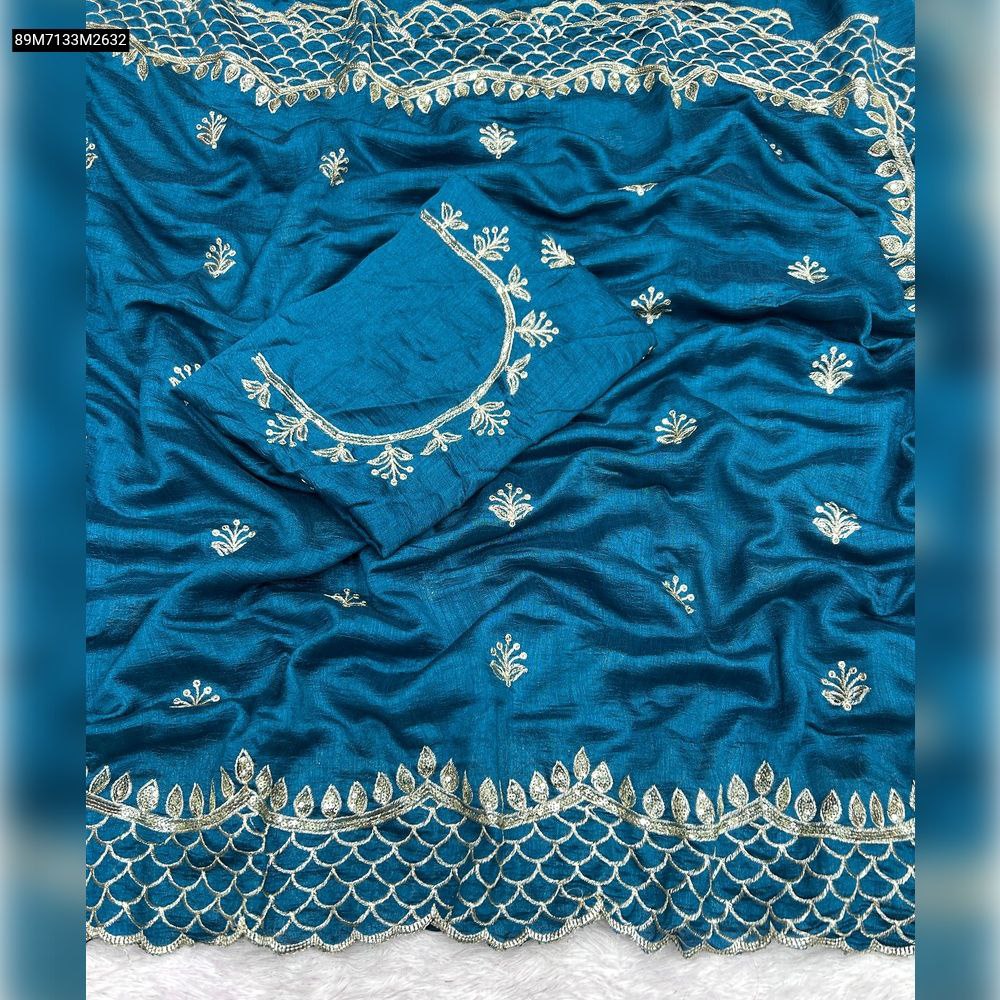 Flat lay of a vibrant teal (peacock blue) TRENDBUY Vichitra silk saree with intricate 3mm sequence embroidery work, showcasing the matching blouse piece.