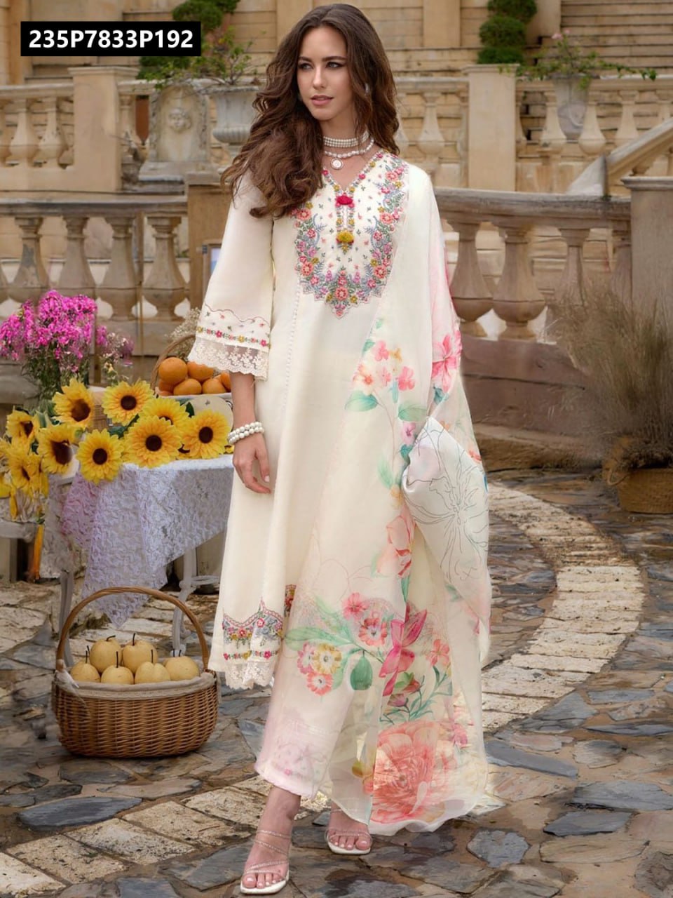 Full body shot of a model elegantly posing in a cream viscose chanderi kurti set featuring intricate embroidery and a flowing floral organza dupatta.