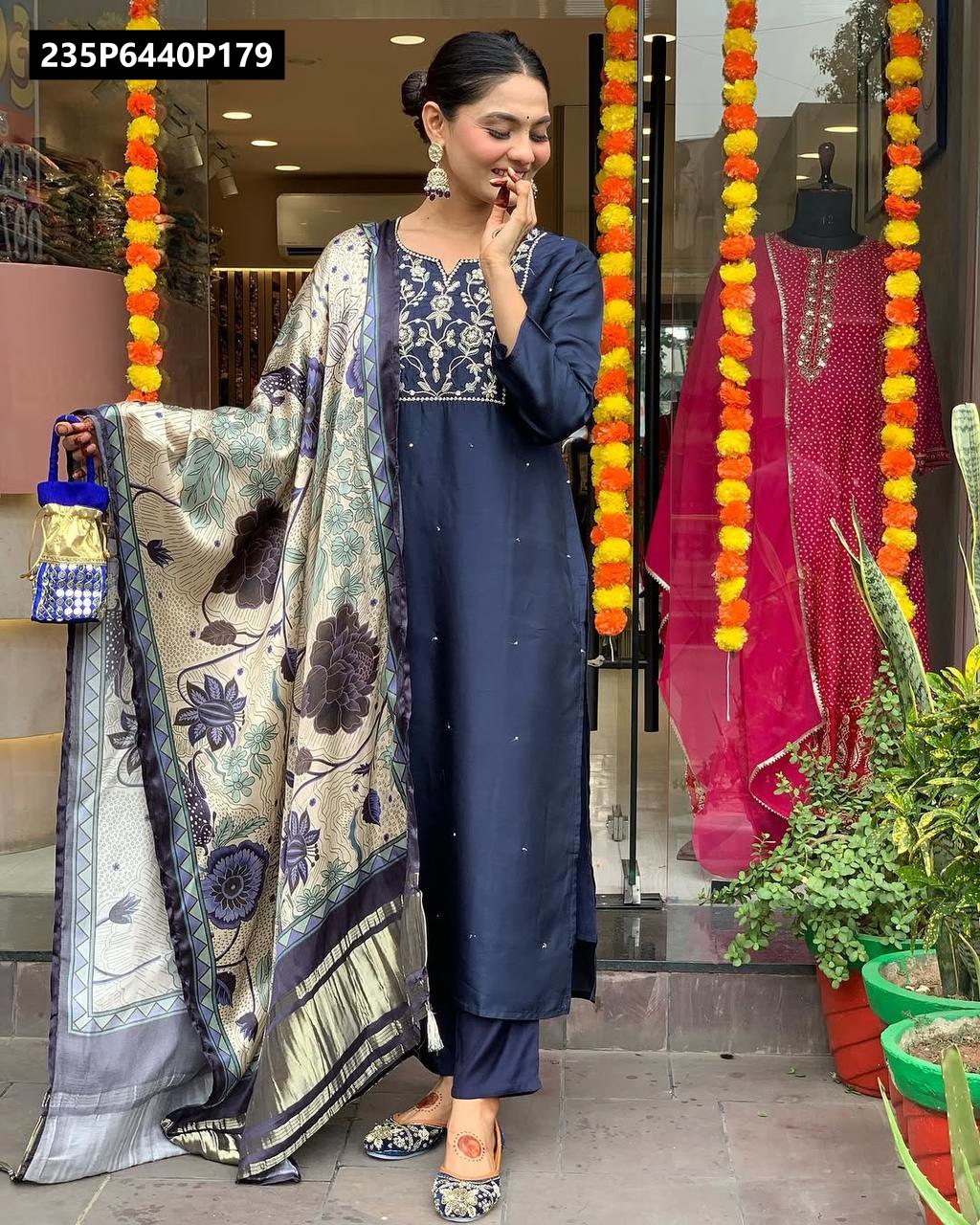 Full body shot of model smiling in TRENDBUY navy blue pure viscose chanderi silk embroidered kurta set with printed dupatta, holding a small potli bag.