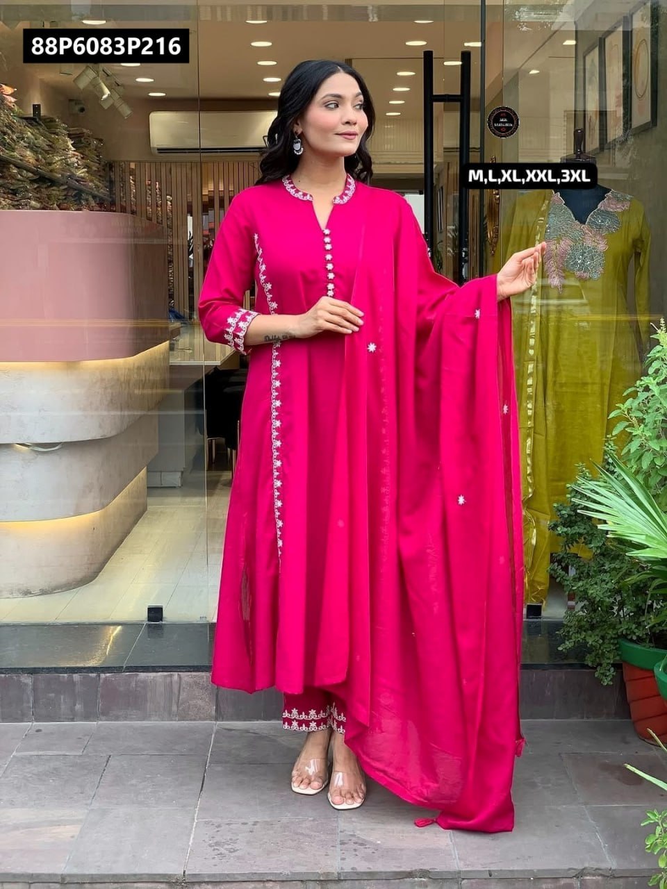 Full body model shot in TRENDBUY hot pink embroidered A-line kurta set with dupatta, posing confidently outside a storefront.