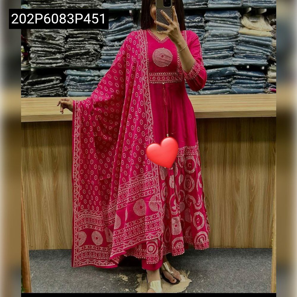 Full body shot of a woman in a vibrant hot pink cotton Anarkali kurta set, featuring white circular prints, sequence work on the V-neck yoke, and a flowing tiered skirt, holding a red heart.