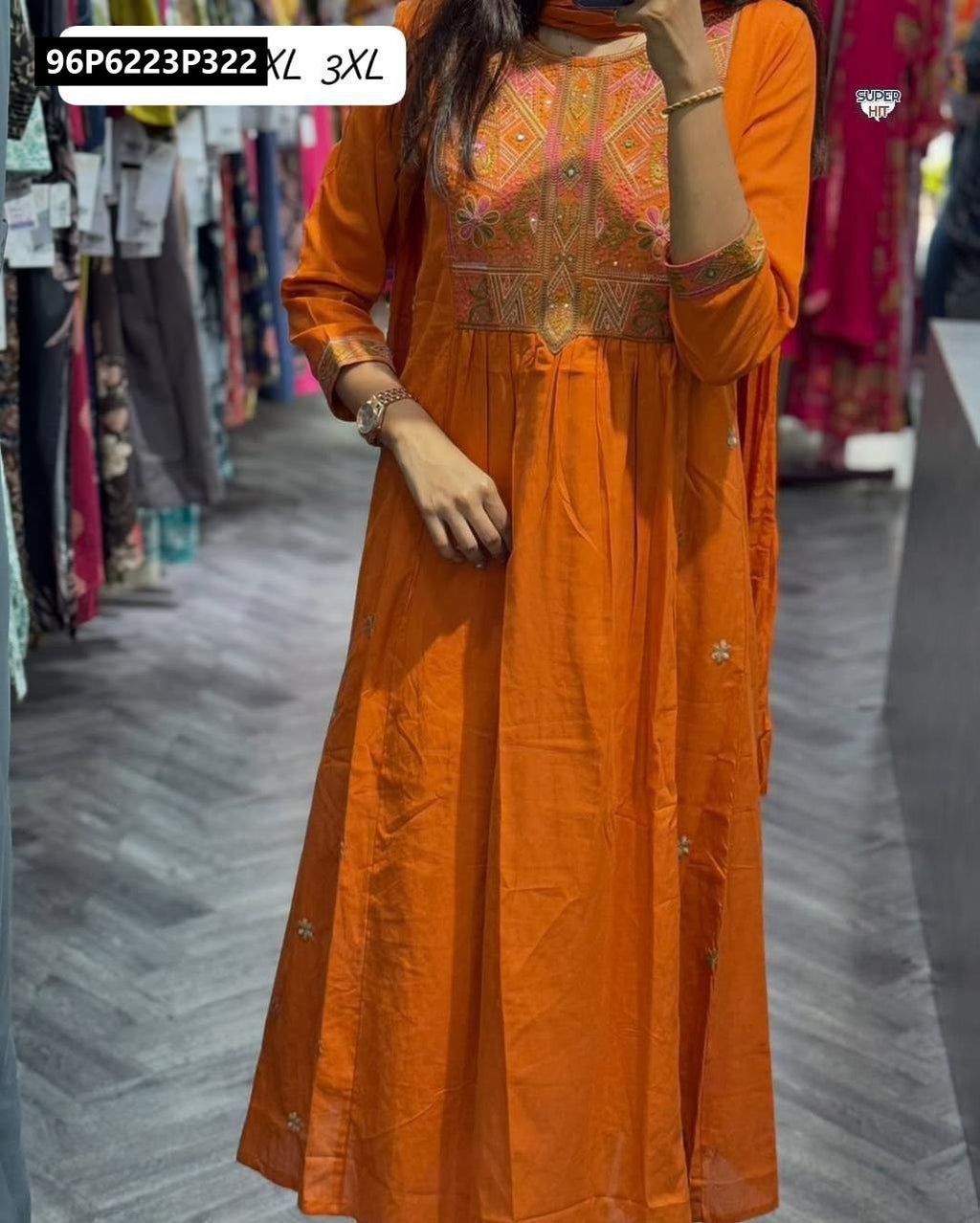 Model wearing an orange TRENDBUY embroidered anarkali kurta set with cotton pant and malmal dupatta, showcasing the full design in a retail setting.