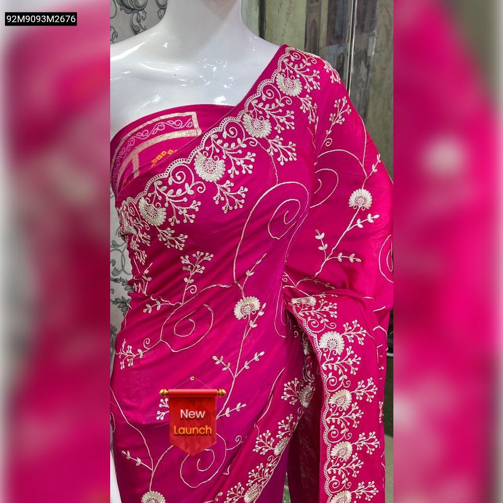 Close-up of a vibrant magenta/rani pink heavy cotton saree showcasing intricate white floral zari embroidery on the pallu.