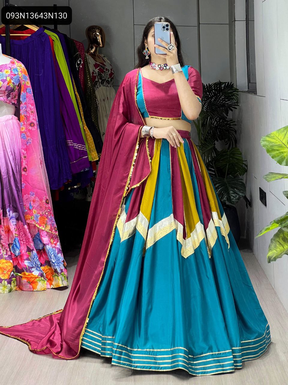Model showcasing a vibrant multi-color Chinon lehenga choli set with a magenta blouse and dupatta, featuring traditional embellishments and a flowing skirt.