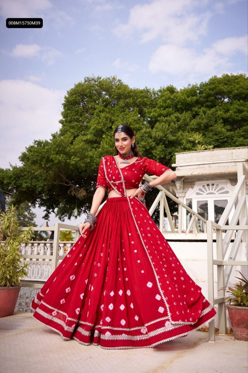 TRENDBUY Women's Red Bandhej Chanderi Lehenga Choli with lace detail, model showcasing full flair against a white building and green tree background.