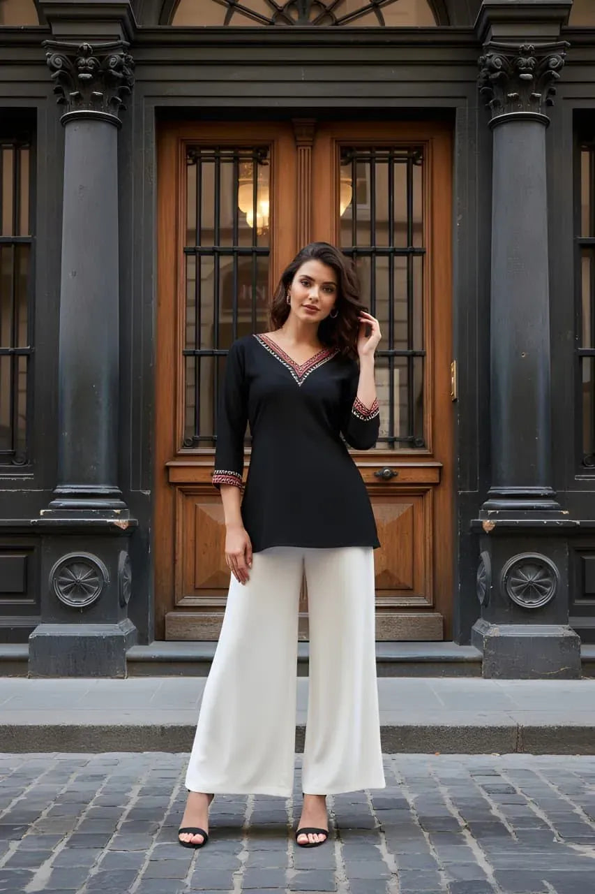 Full-body shot of model wearing black printed V-neck tunic top with white palazzo pants