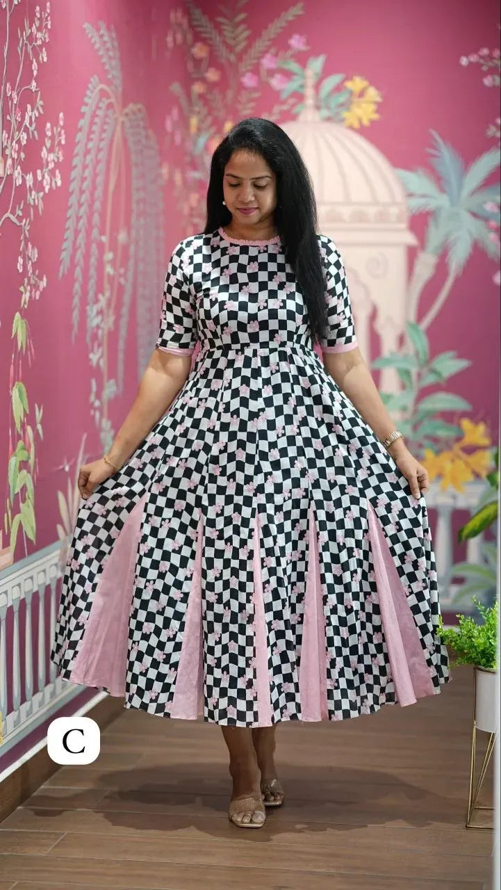 Model wearing black and white checkered dress against pink floral wall