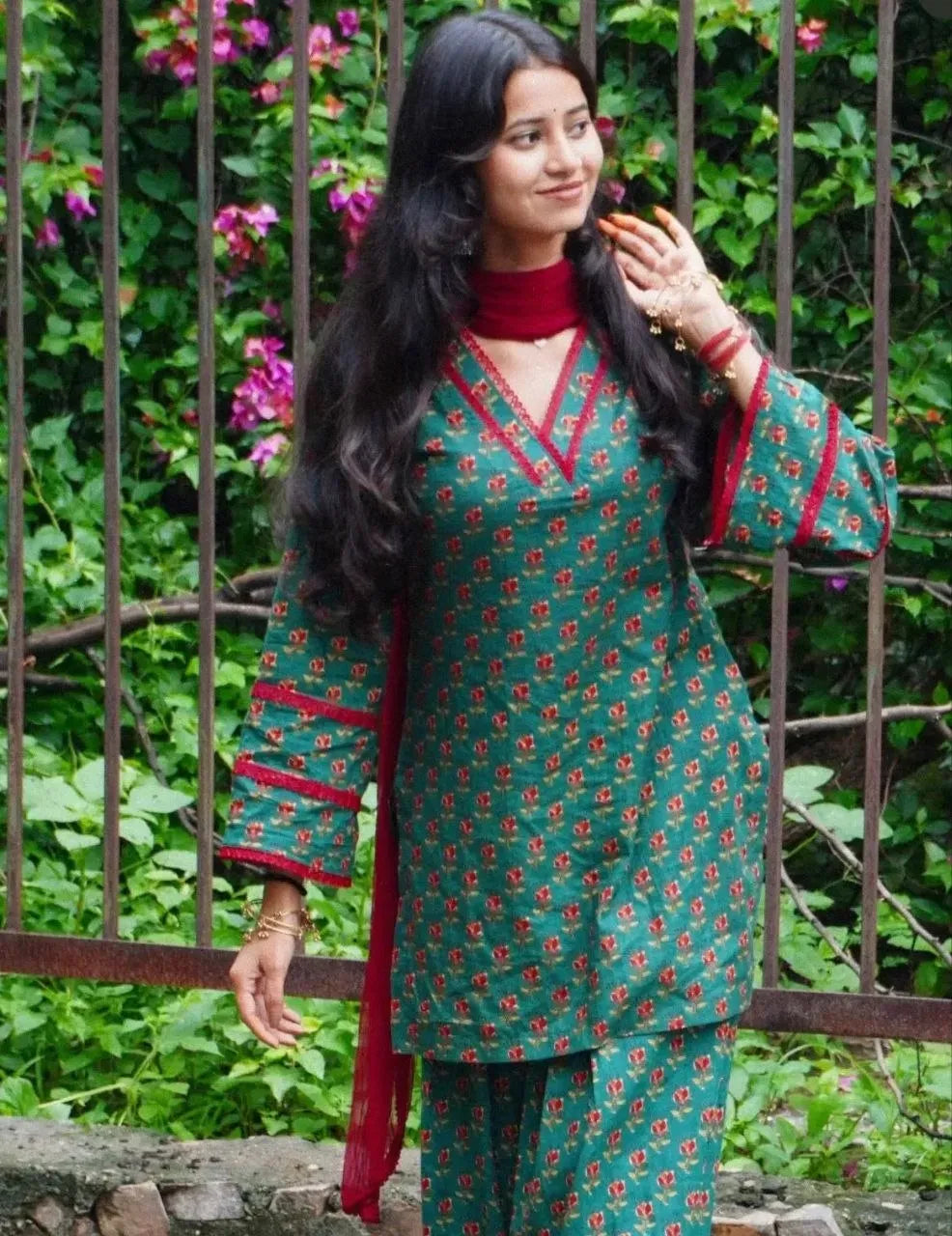 Full body shot of model wearing green block print farshi salwar set near plants