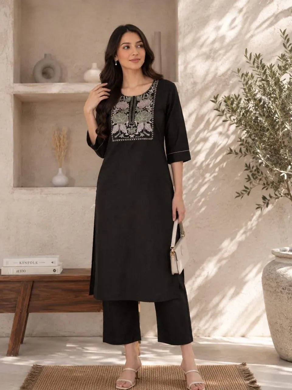 Front full view of woman wearing black embroidered flex cotton kurti set holding a handbag