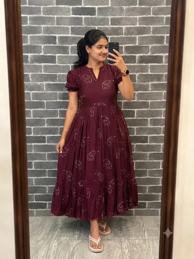 Model standing in front of grey brick wall wearing maroon anarkali