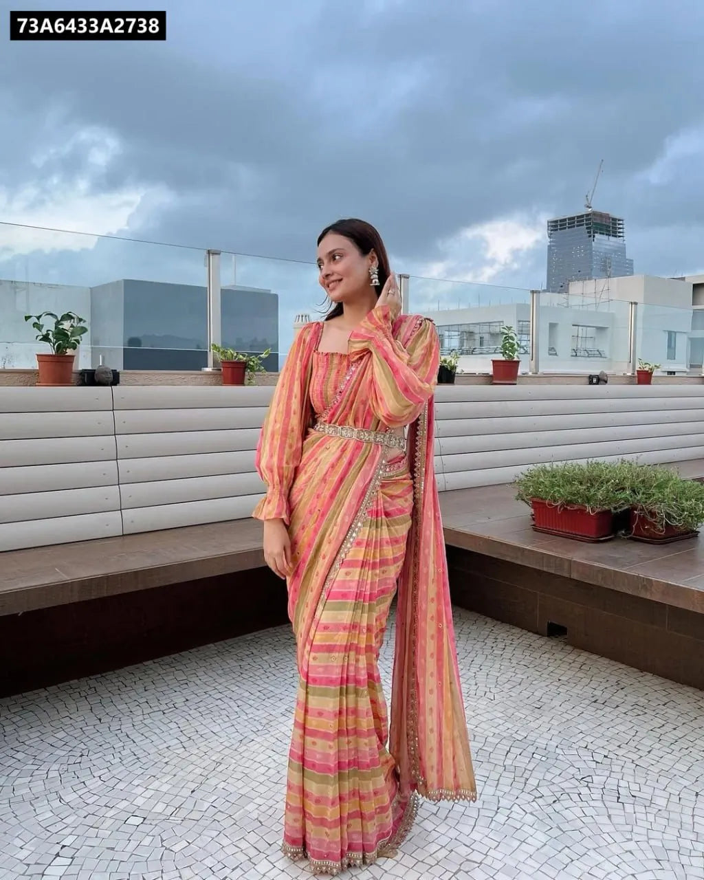 Model wearing TRENDBUY multicolor striped Georgette saree with contemporary blouse and belt on a rooftop