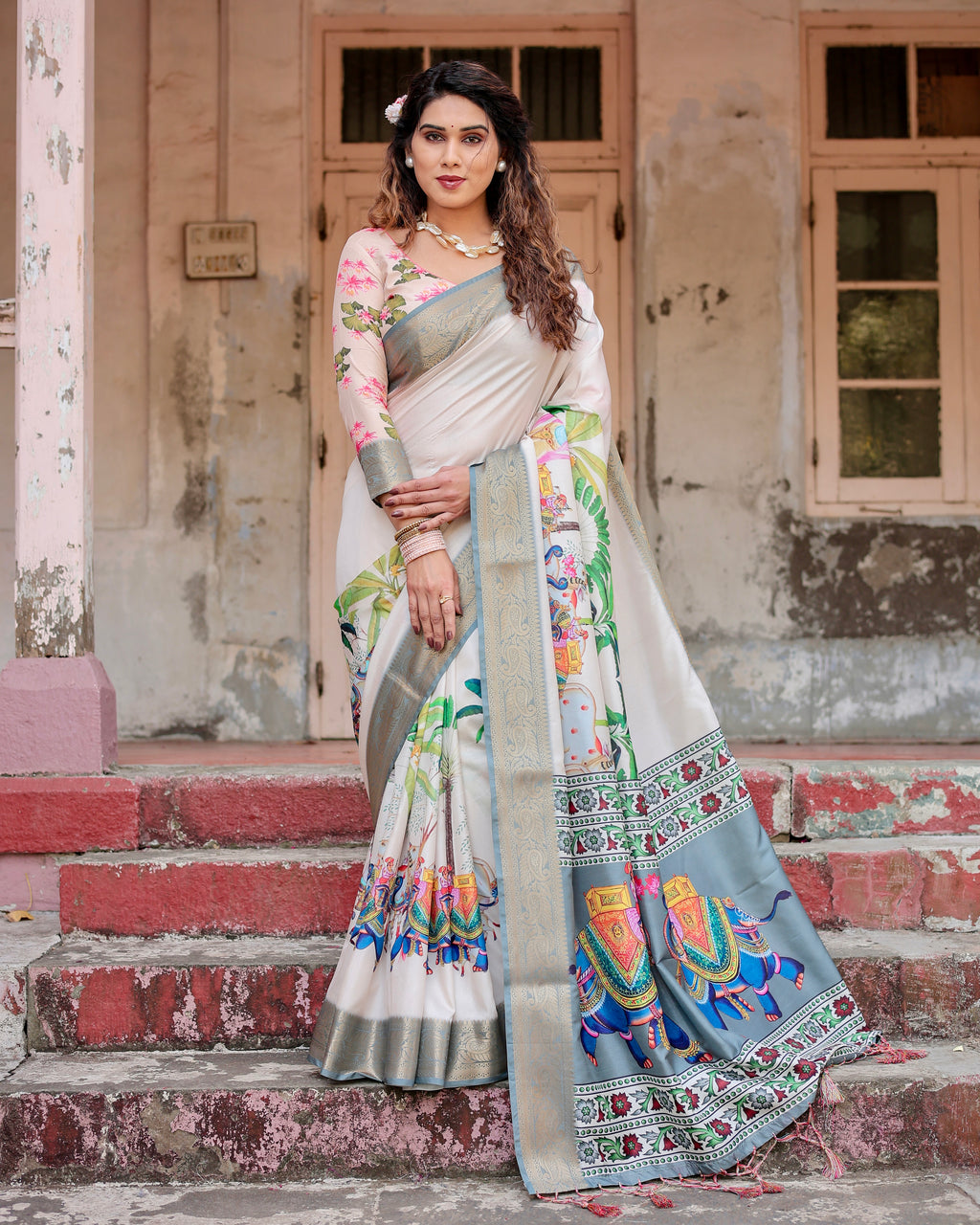 Woman wearing a Royal Heritage Tussar Silk Saree with elephant digital print and zari border in Ivory and Silver-Blue color, posing gracefully.